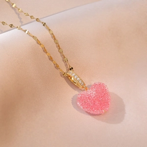 Macro detail of a candy pink heart pendant on a gold flat link chain necklace
