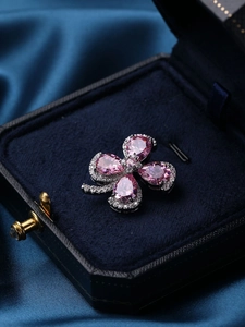 Macro detail of a pink four-leaf clover brooch with teardrop stones in a velvet gift box