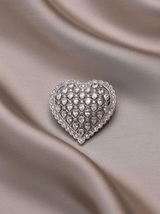 Detail of silver heart brooch with pear-shaped cubic zirconia on champagne silk