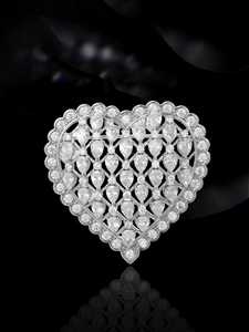 Detailed macro shot of a heart-shaped silver brooch with intricate crystal pavé setting