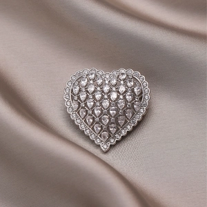 Elegant silver heart brooch with sparkling zircon stones on champagne silk background