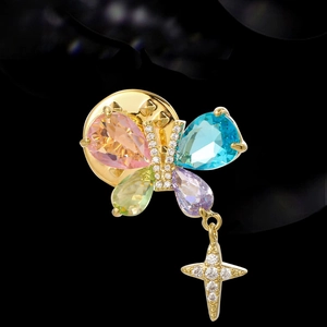 Golden butterfly brooch with colorful pear-cut gemstones and a sparkling star pendant