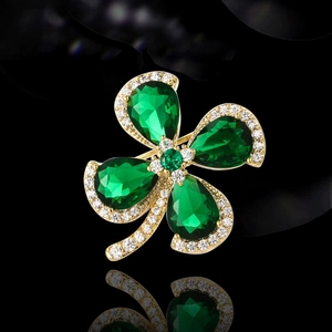 Vintage emerald green four-leaf flower brooch with gold plating and sparkling accents