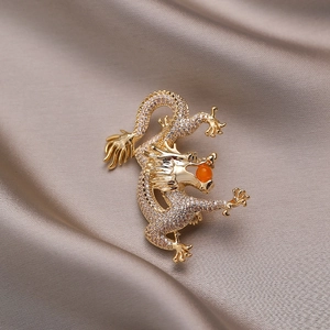 Exquisite golden dragon brooch with micro-set zircons and orange bead on silk background