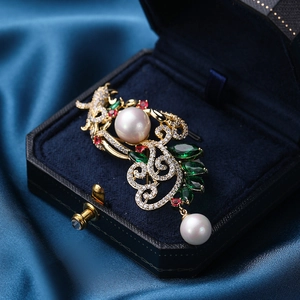 Eleganter Gold-Phönix-Anstecknadel mit Perlen und grünen Zirkonen auf blauem Samt