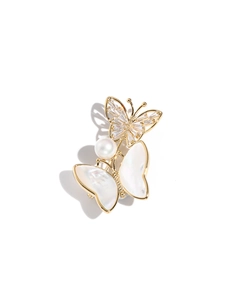 Close-up of golden butterfly brooch with mother-of-pearl shell and white pearl detail