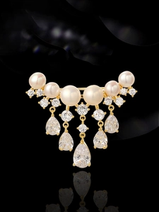 Detail of luxury gold brooch with white pearls and dangling pear-cut zircon stones