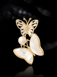 Detail of vintage double butterfly brooch with natural shell, pearls and cubic zirconia