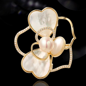 Gouden camelia broche met parelmoer hartblaadjes en parel op een zwarte achtergrond