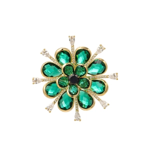 Close-up of emerald green flower brooch with zircon stones on gold-plated metal base