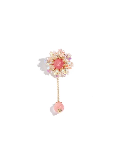Close-up of a pink floral brooch with iridescent petals and gold chain drop detail