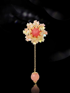Detail of floral brooch featuring a pink crystal stone and iridescent petals on gold chain