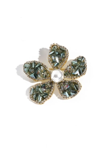 Detail einer fünfblättrigen Blütenbrosche mit grünen Steinen, Strass und einer Perle