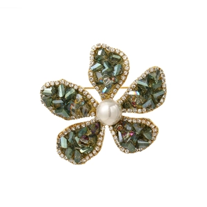 Makrodetail einer goldenen Blumenbrosche mit grünen Edelsteinen, Perlen und Mikro-Kristallen
