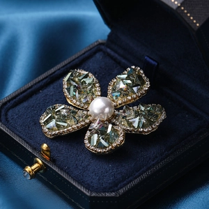 Elegante Blumenbrosche mit türkisfarbenen Blättern und Perle in einer blauen Samtbox