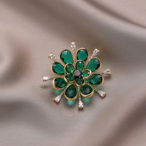 Elegant emerald green flower brooch with zircon crystals on champagne silk fabric