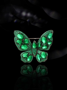 Detailed view of vintage butterfly brooch featuring green rhinestones on dark metal base