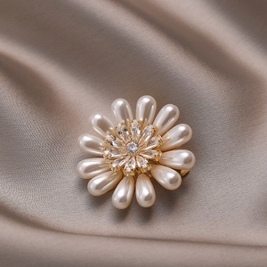 Broche fleur dorée avec perles en goutte et zircons brillants sur fond en soie satinée