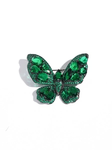 Detail of vintage butterfly brooch with emerald green crystals and black metal setting