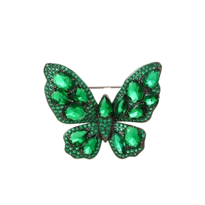 Detailed close-up of emerald green butterfly brooch with teardrop crystals and black alloy