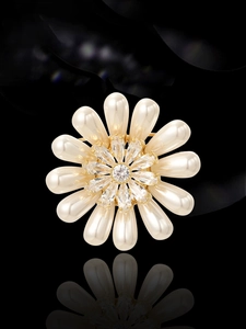 Gros plan d'une broche florale avec perles crème et zircons sur un fond de miroir noir