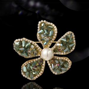 Eleganter Blumenbrosche mit grünen Kristallen, weißen Strasssteinen und Perle auf Goldbasis