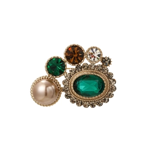 Vue détaillée d'une broche vintage dorée avec cristal émeraude et perle champagne