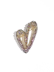 Détail d'une broche en forme de cœur avec cristaux violets et perles sur base dorée