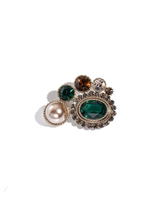 Vue détaillée d'une broche vintage avec émeraude, perle blanche et base en or antique