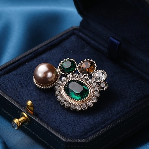 Broche vintage avec pierre vert émeraude et perle brune dans un coffret en velours