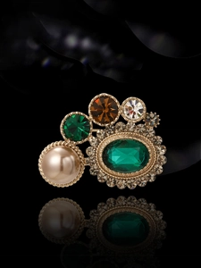 Vue macro d'une broche vintage dorée avec cristal vert émeraude et perle champagne
