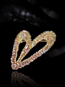 Détail d'une broche en forme de cœur avec cristaux arc-en-ciel et strass dorés