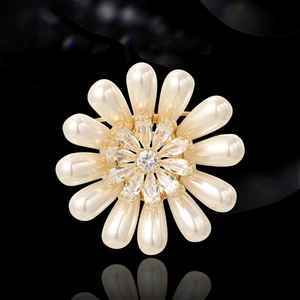 Broche fleur dorée élégante avec perles et zircons sur une surface noire réfléchissante