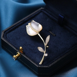 Elegante gouden tulpenbroche met witte schelpblaadjes en zirkonia in een blauwe doos