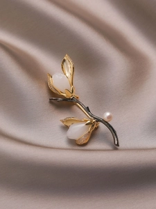 Détail de la broche magnolia avec bourgeons blancs, touches dorées et une perle