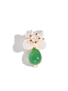 Macro shot of white shell flower brooch with pearl center and green teardrop gemstone