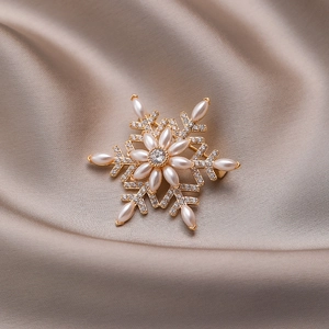 Elegant rotating snowflake brooch with gold-plated base, white pearls, and sparkling cubic zirconia