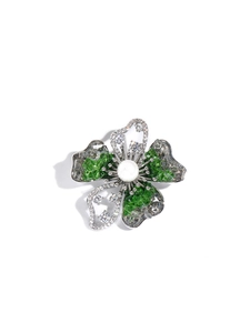 Macro shot of silver flower brooch with green crystals and a white pearl center