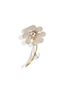 Detail of flower brooch with pearl center and pavé crystals on a golden stem