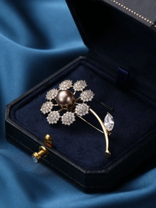 Detailed close-up of a floral pearl brooch with zircons on blue velvet
