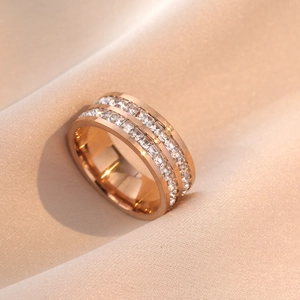 Gros plan d'une bague en or rose avec double rangée de zircons sur soie champagne
