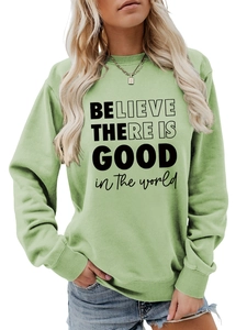 Dettaglio felpa verde chiaro con stampa di lettere nere 'BELIEVE THERE IS GOOD' sul petto