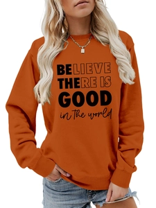 Dettaglio felpa arancione girocollo con stampa motivazionale 'Believe there is good'