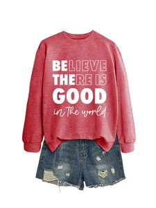Dettaglio della felpa rossa con stampa 'BELIEVE THERE IS GOOD' e pantaloncini denim