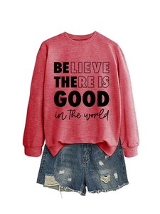 Dettaglio della felpa rossa con stampa 'BELIEVE THERE IS GOOD' e shorts in denim
