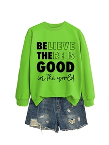 Dettaglio di una felpa verde neon con scritta e pantaloncini in denim strappati