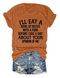 Flat lay of an orange crew neck T-shirt with black slogan and distressed blue denim shorts