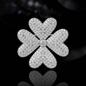 Glitzernde silberne Kleeblatt-Brosche mit Strasssteinen auf reflektierender Oberfläche
