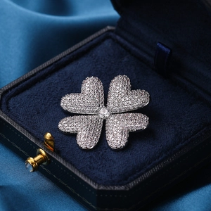 Funkelnde Kleeblatt-Brosche mit weißen Kristallen auf elegantem blauem Samtetui