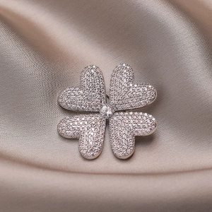 Funkelnde Kleeblatt Brosche mit Zirkonia-Steinen auf elegantem Satin Hintergrund